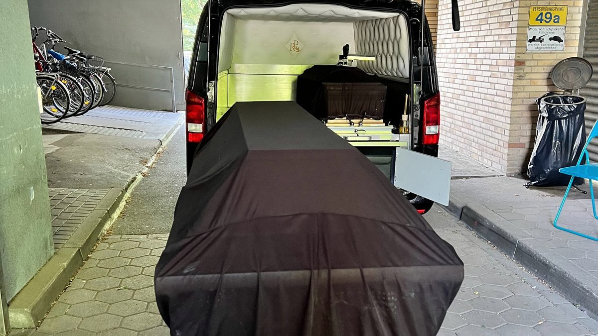 Ритуальний автомобіль із труною біля будівлі перед церемонією прощання