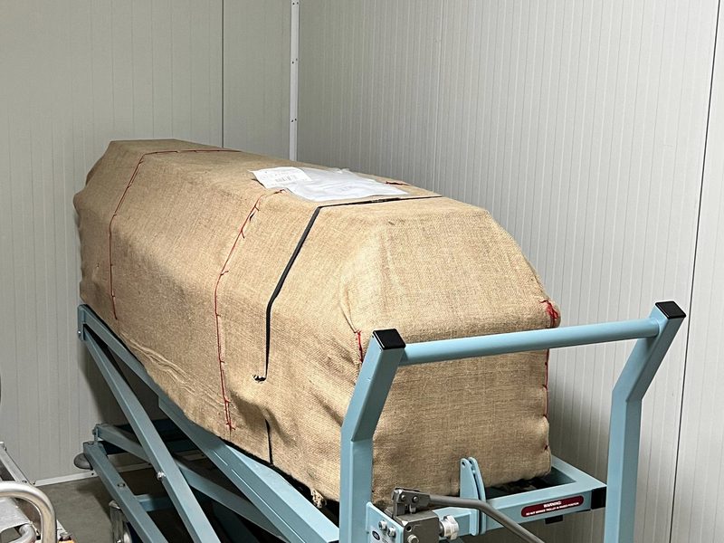 Цинкова труна в дерев'яному ящику на візку для транспортування до крематорію