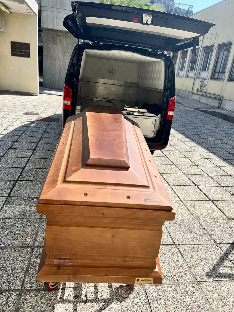 Дерев'яна труна для міжнародного перевезення біля ритуального автомобіля